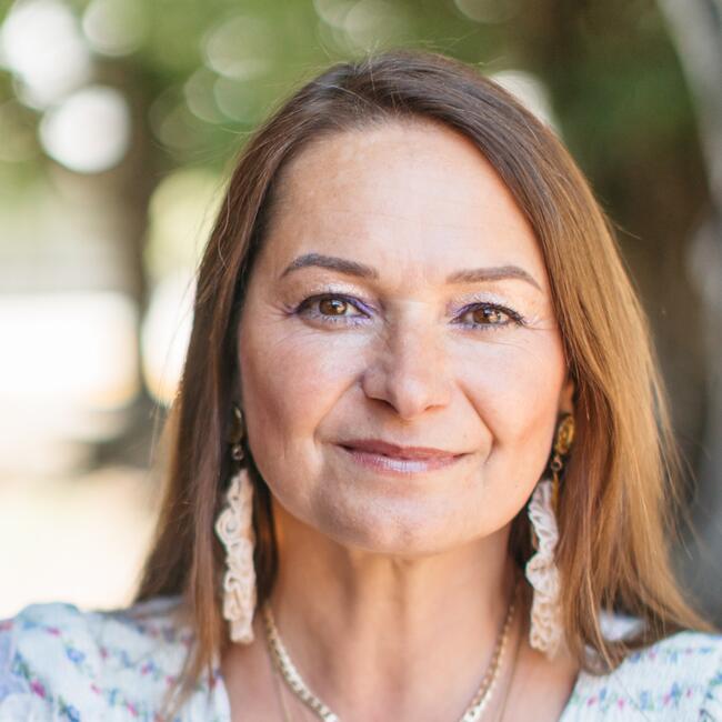 Aleksandra Sikora smiles at camera wearing earrings and necklaces outside