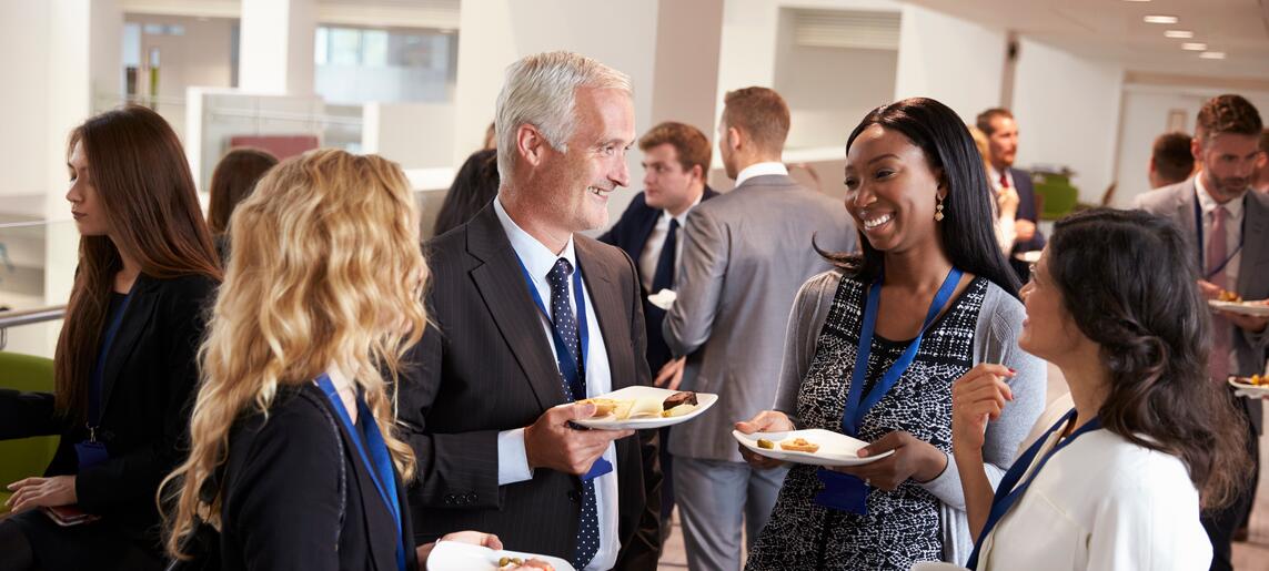 A group of older professionals speak in a circle while eating