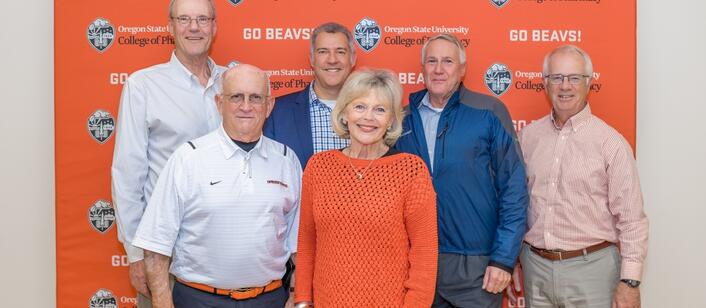 A group of Dean's Circle members and Dean David Bearden stand in front of an OSU College of Pharmacy Banner 