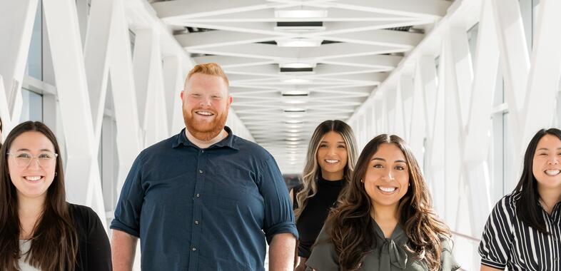 Group of students in ohsu skybridge smiling while walking towards camera
