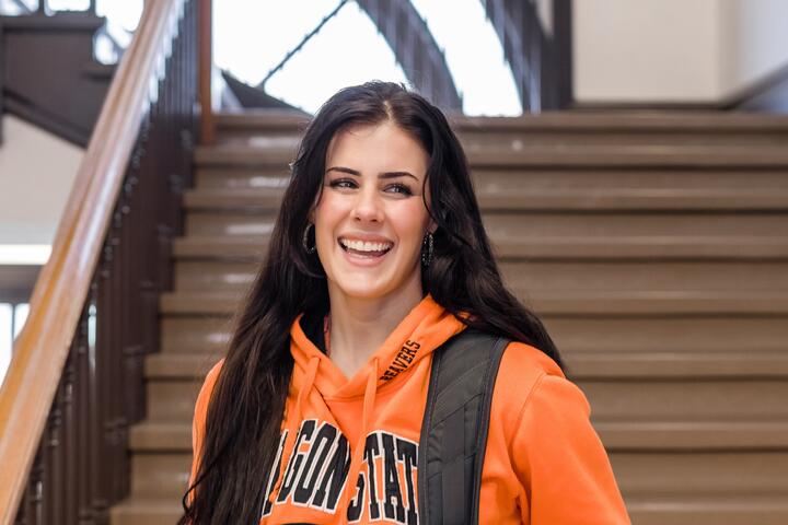 A girl looks at the camera, smiling, wearing beaver gear in the college of pharmacy